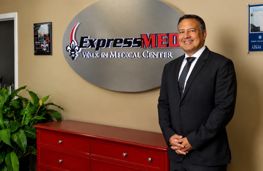Dr. R. John Higginbotham, Medical Director, beside the ExpressMED sign in the clinic lobby