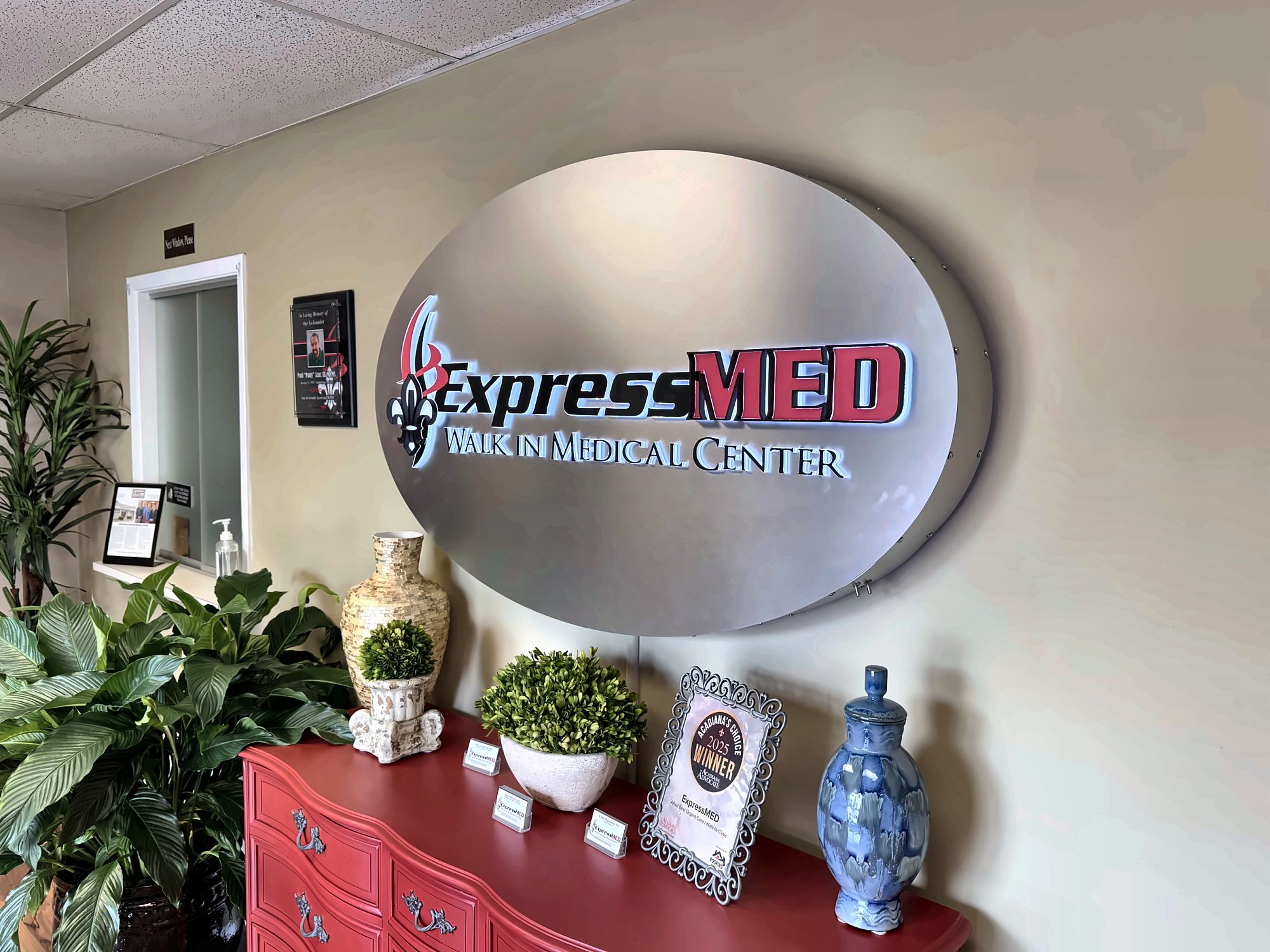 The lighted ExpressMED Walk In Medical Center sign above a red cabinet in the clinic lobby